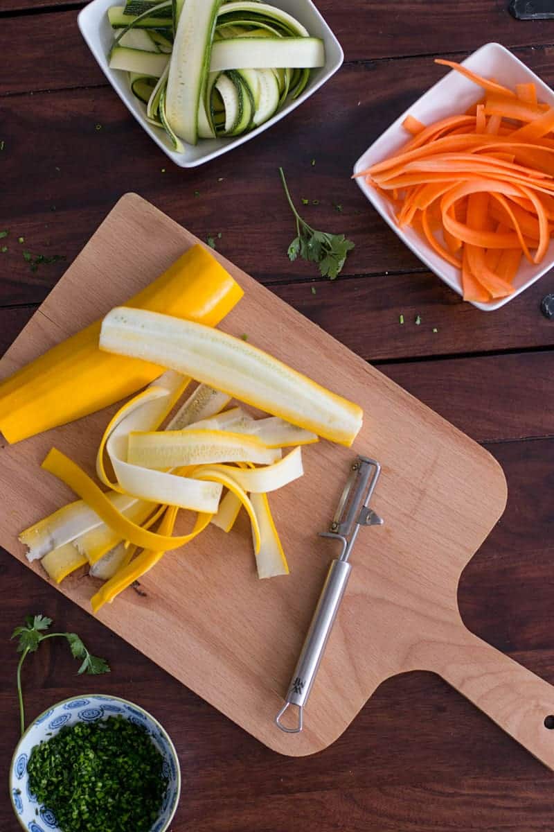 top down view on chopping board with ribboned carrots and summer squash