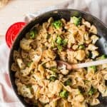 red cast iron skillet with pasta on a wooden board