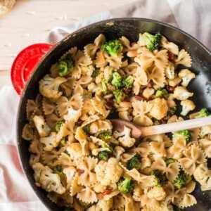 red cast iron skillet with pasta on a wooden board