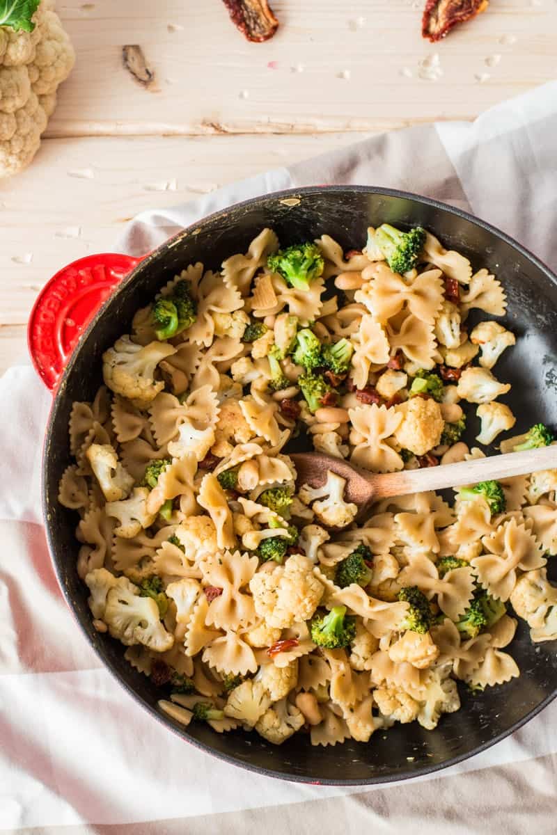 red cast iron skillet with pasta on a wooden board