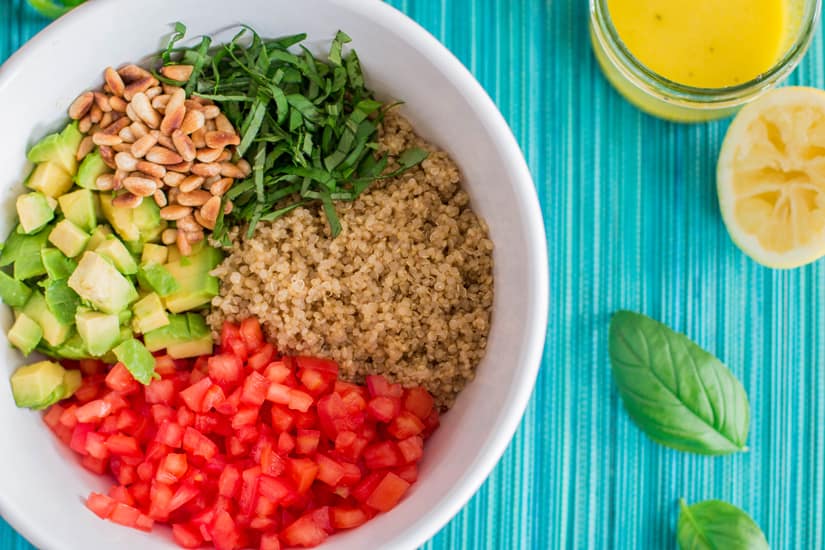 top down view on white bowl with ingredients for quinoa salad