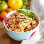 floral bowl with couscous salad in front of colourful tomatoes