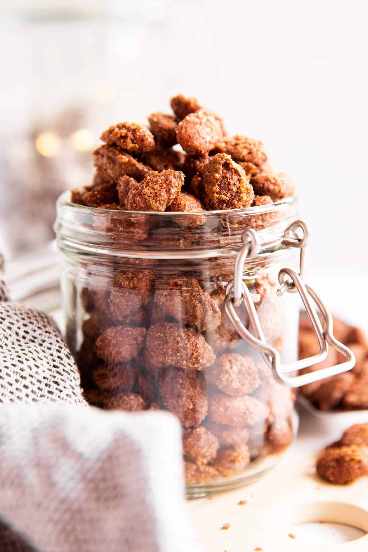 glass jar filled with candied almonds in front of twinkle lights