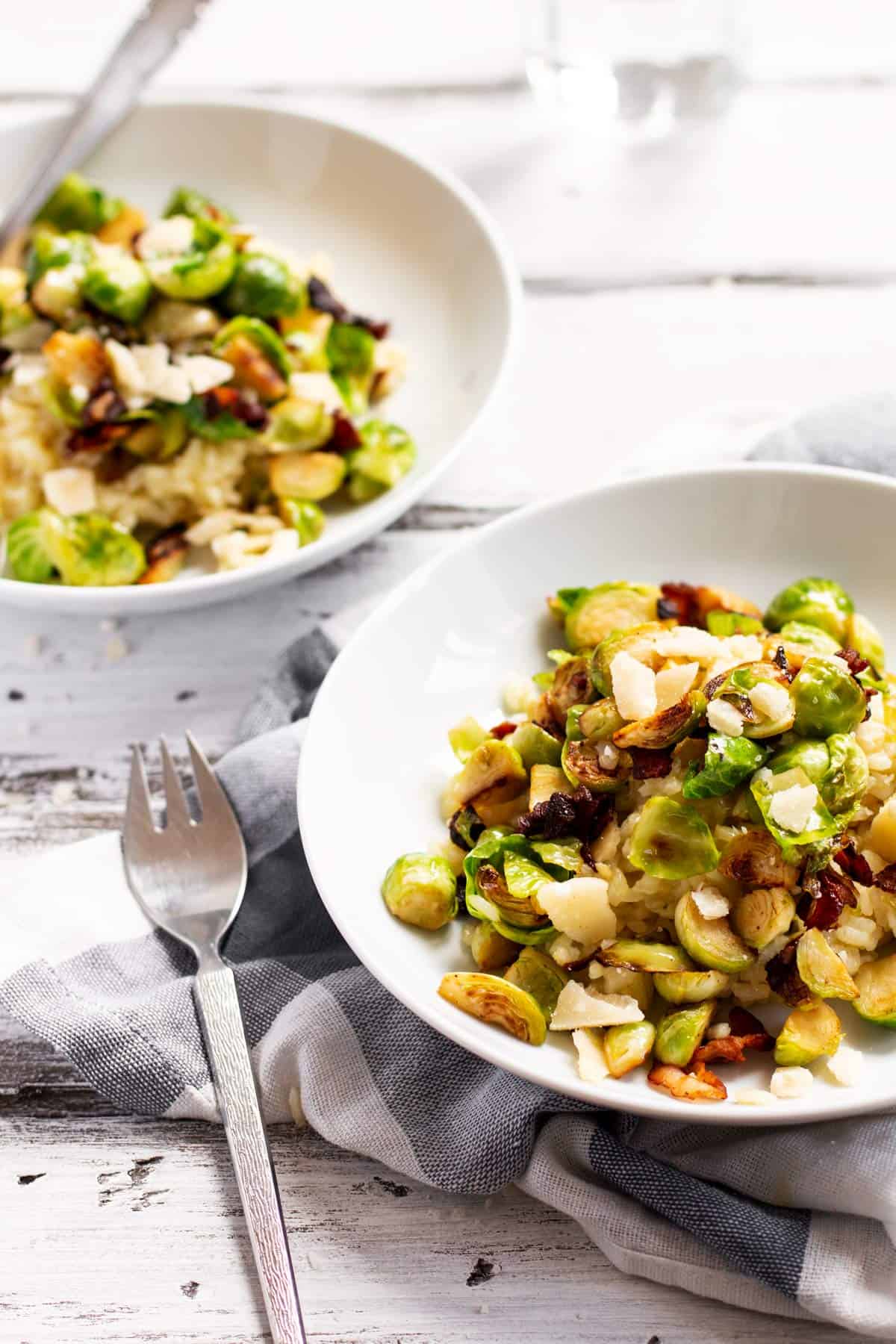 two plates filled with risotto with bacon and brussels sprouts