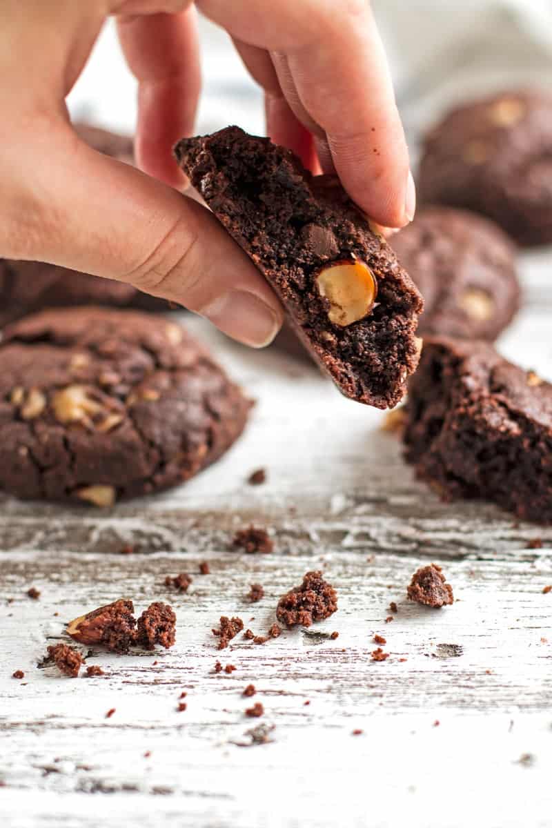 Female hand holding half a chocolate hazelnut cookie.