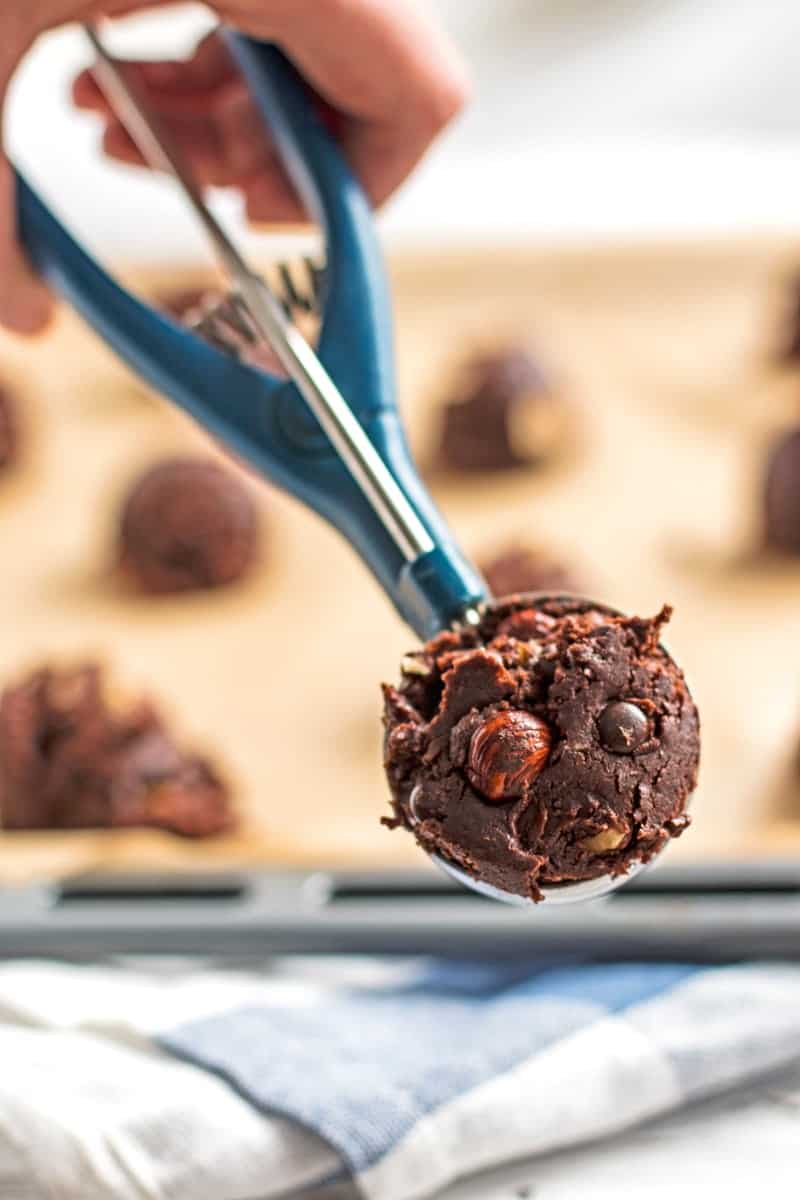 Hand holding a cookie scoop with chocolate cookie dough