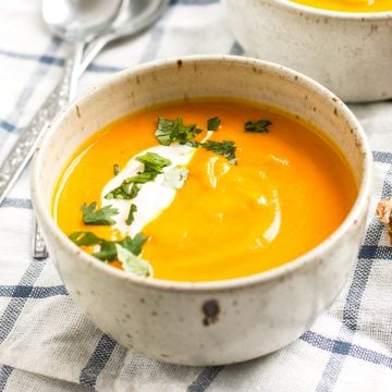 frontal view of white bowl filled with carrot soup