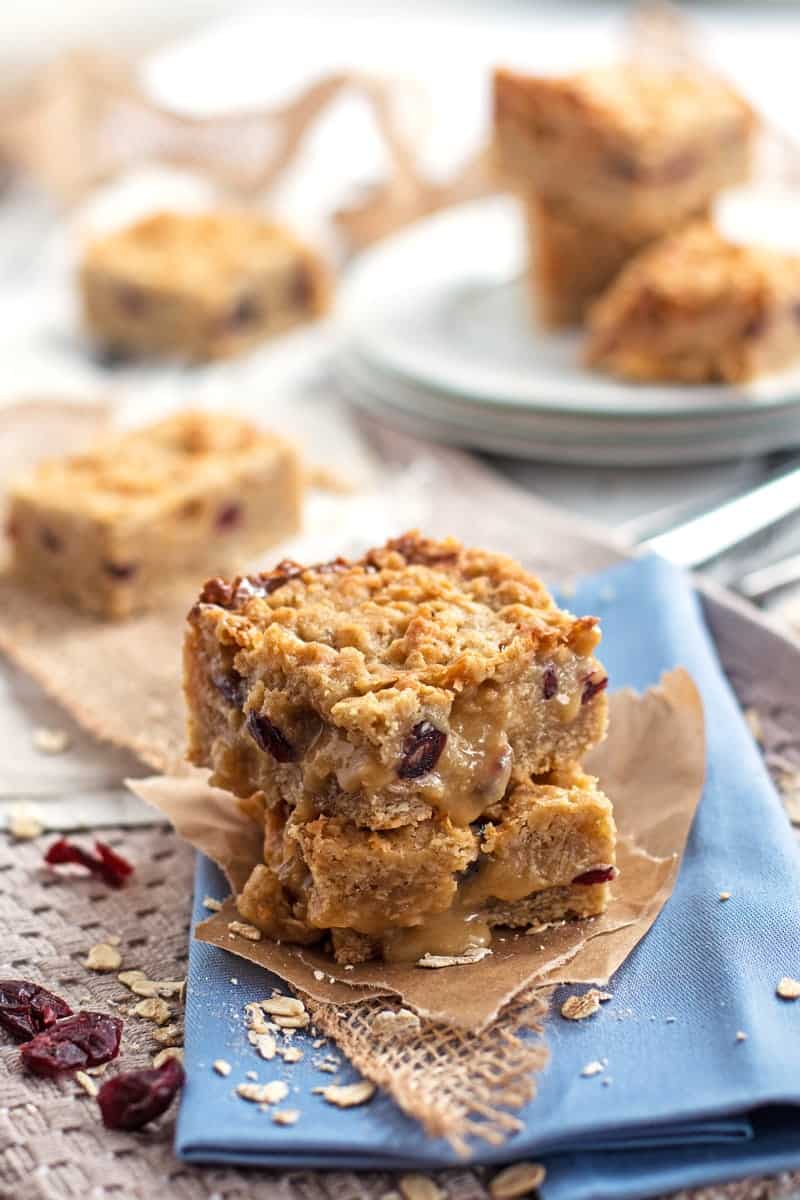 frontal view of tables cape with cranberry oatmeal bars on whir^te plates and blue napkins