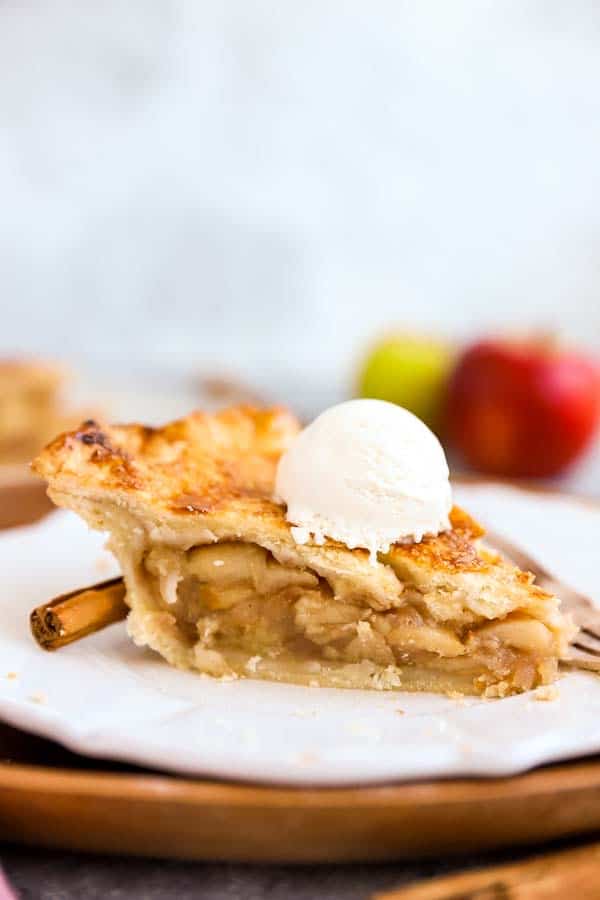 slice of apple pie on a plate, topped with a scoop of vanilla ice cream