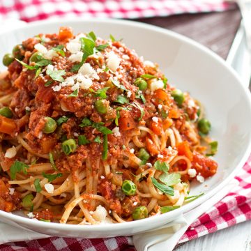 angled view of white plate with spaghetti and meat sauce