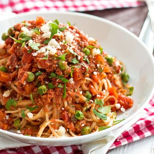 angled view of white plate with spaghetti and meat sauce