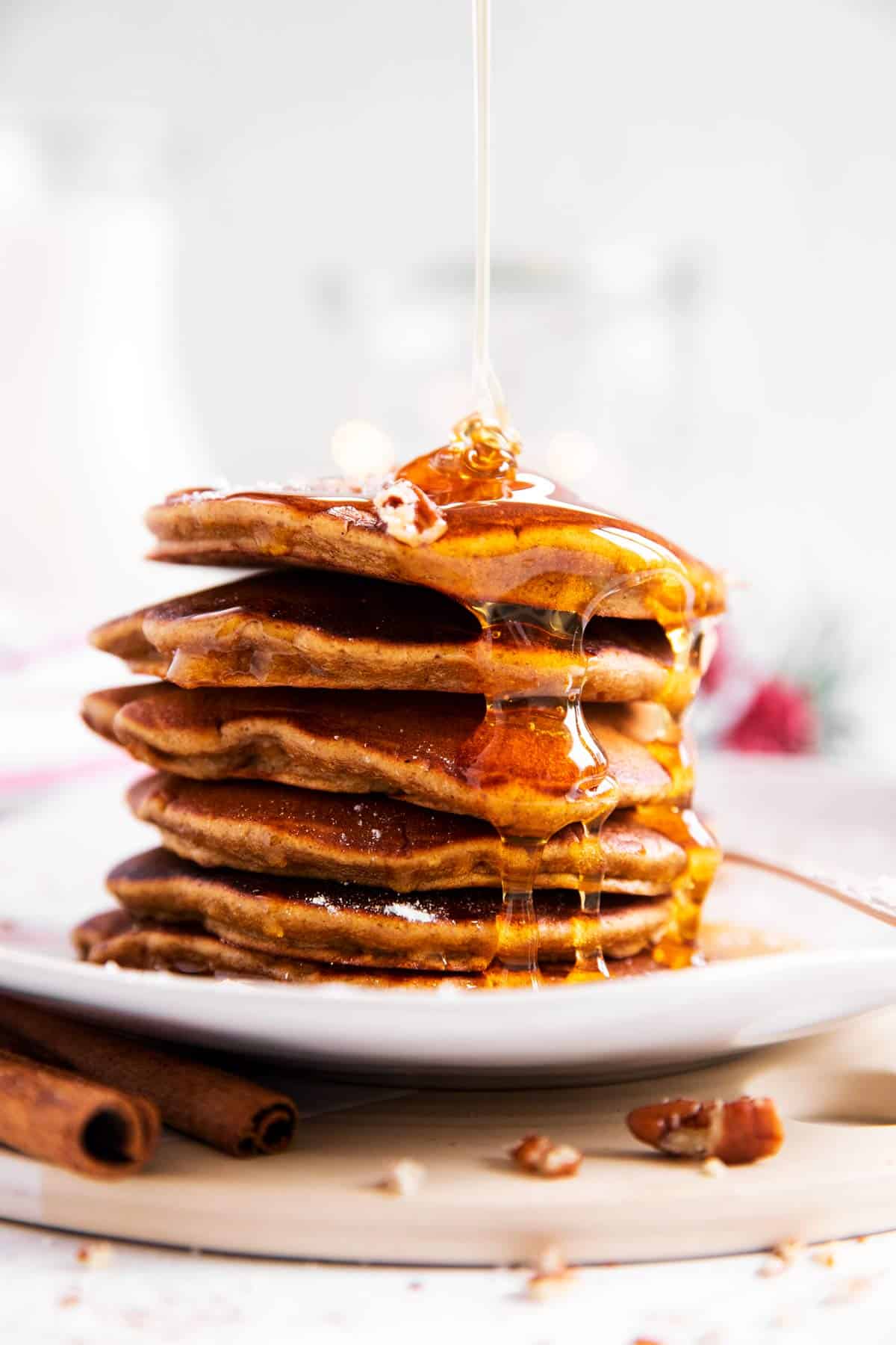 stack of gingerbread pancakes with maple syrup drizzling over