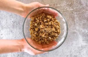 female hands holding a glass bowl with crumble topping