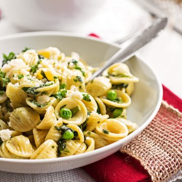 square crop of frontal view on white plate with spinach pea pasta