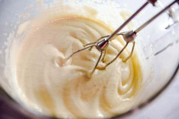 beaten eggs and sugar in a bowl with mixer attachment