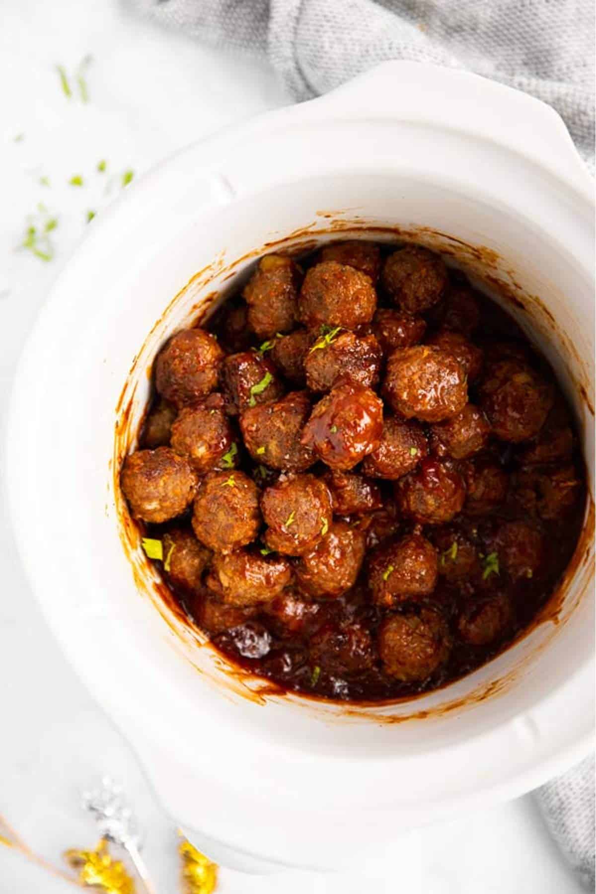 close up of white slow cooker with bbq meatballs