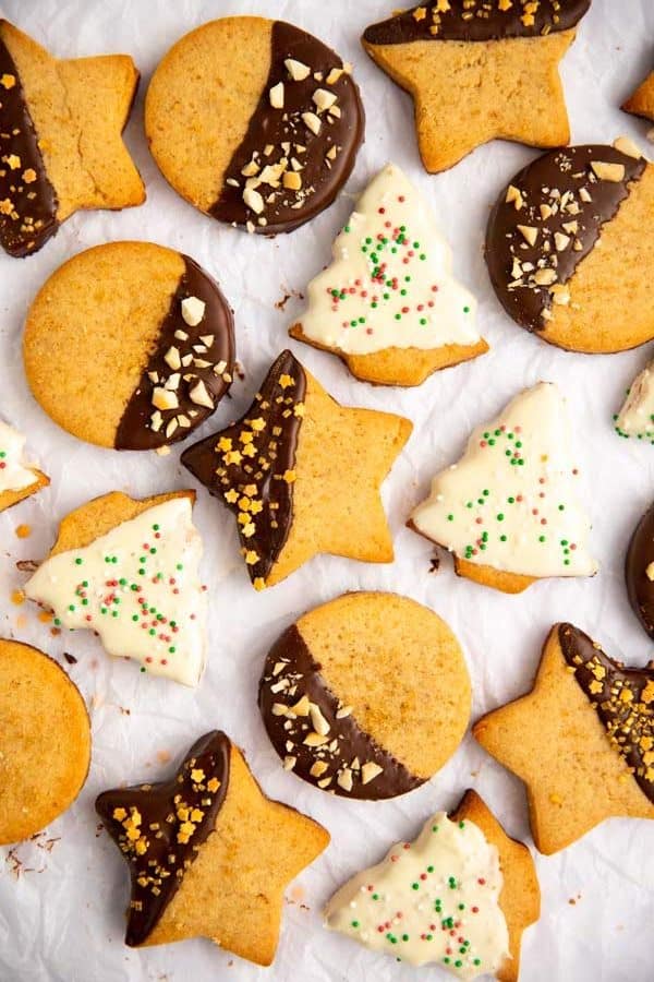 bunch of chocolate dipped shortbread cookies on a piece of baking parchment