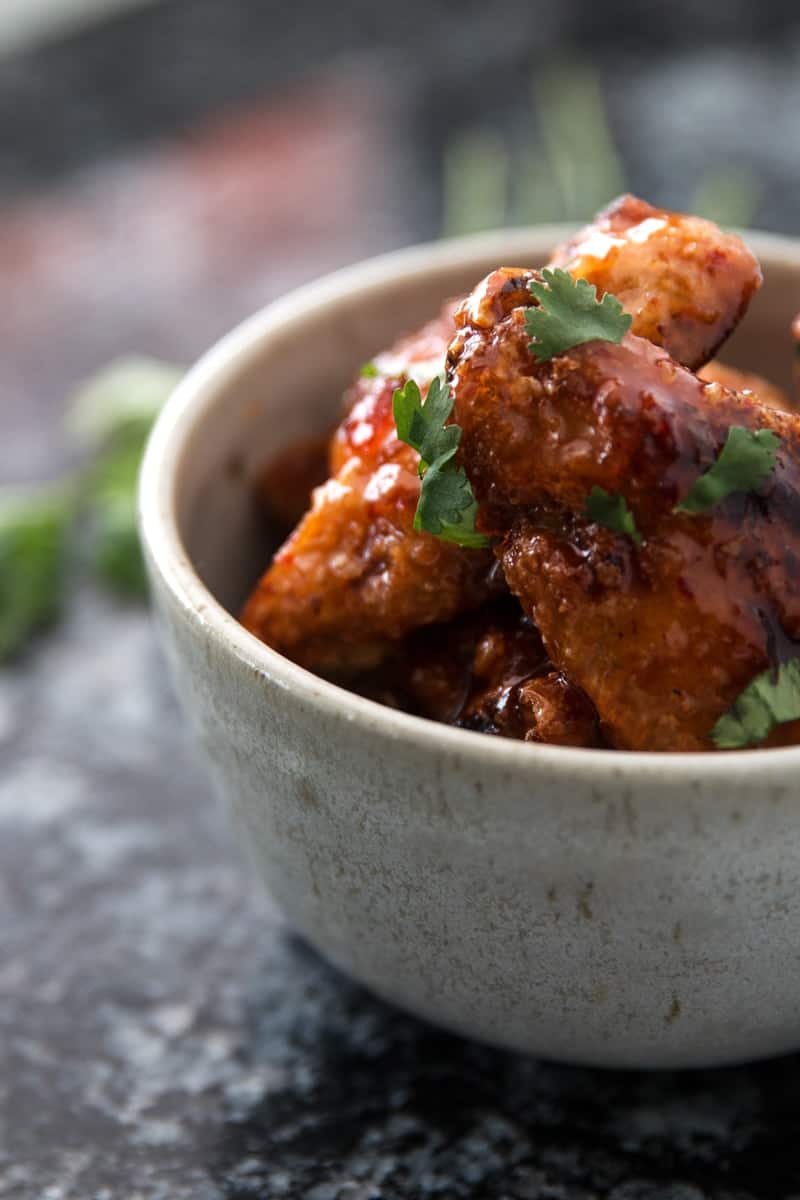 frontal view of sticky chili wings in light colored bowl