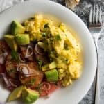top down view on scrambled eggs and citrus salad on white plate