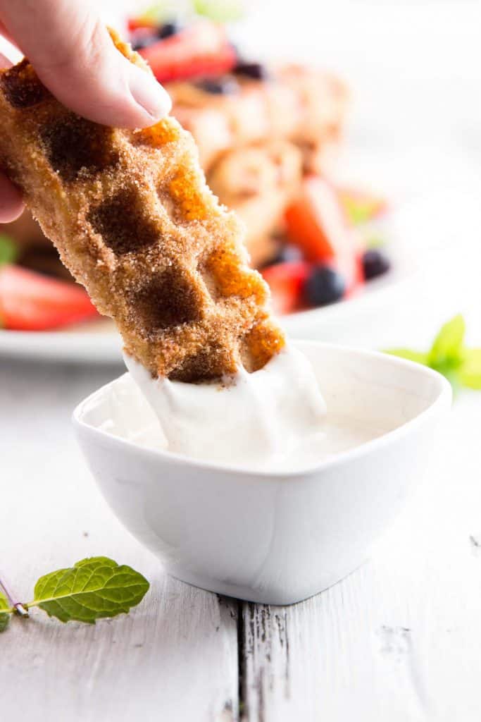 dipping a french toast waffle stick into cream cheese