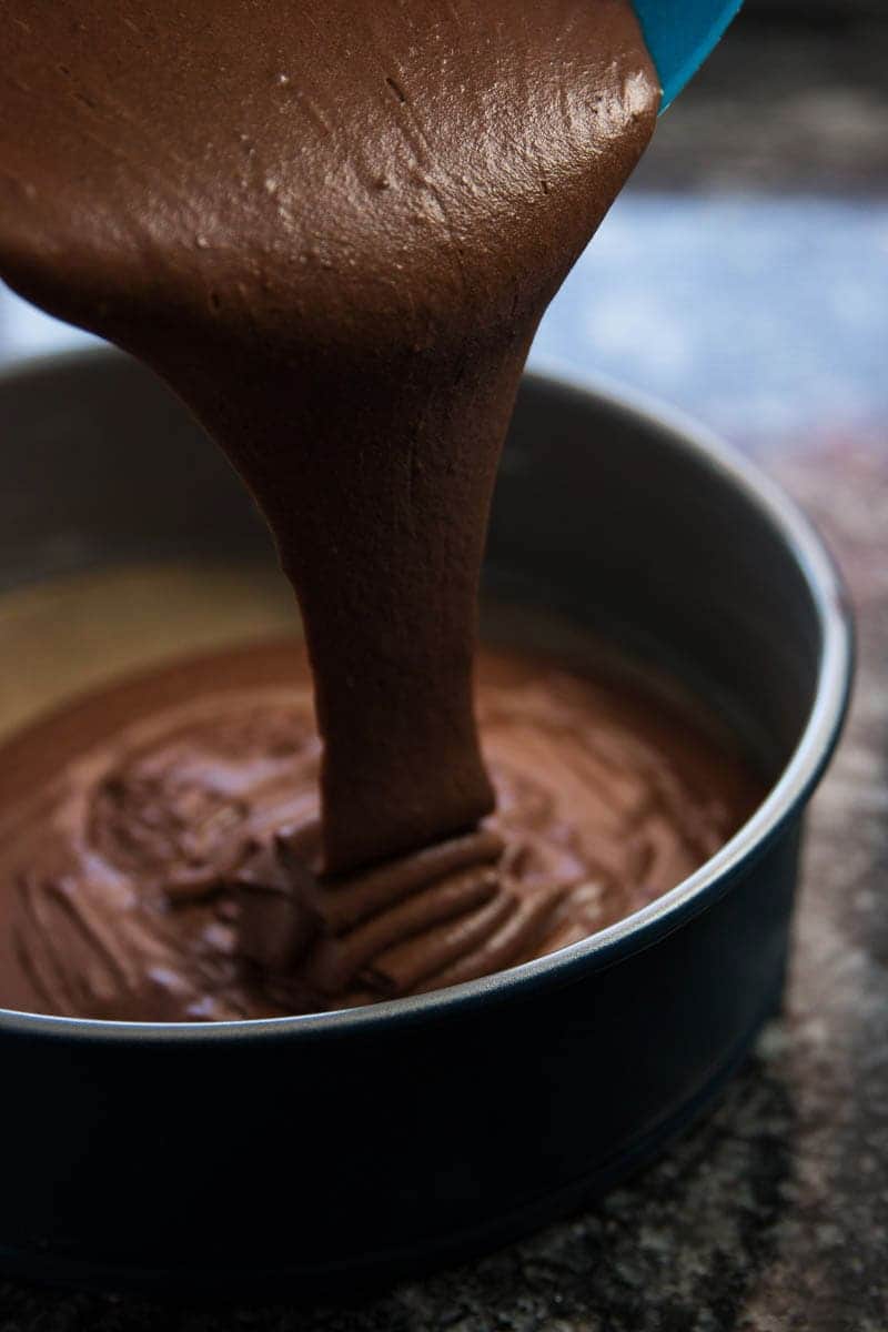 photo of chocolate cake batter pouring into round cake pan
