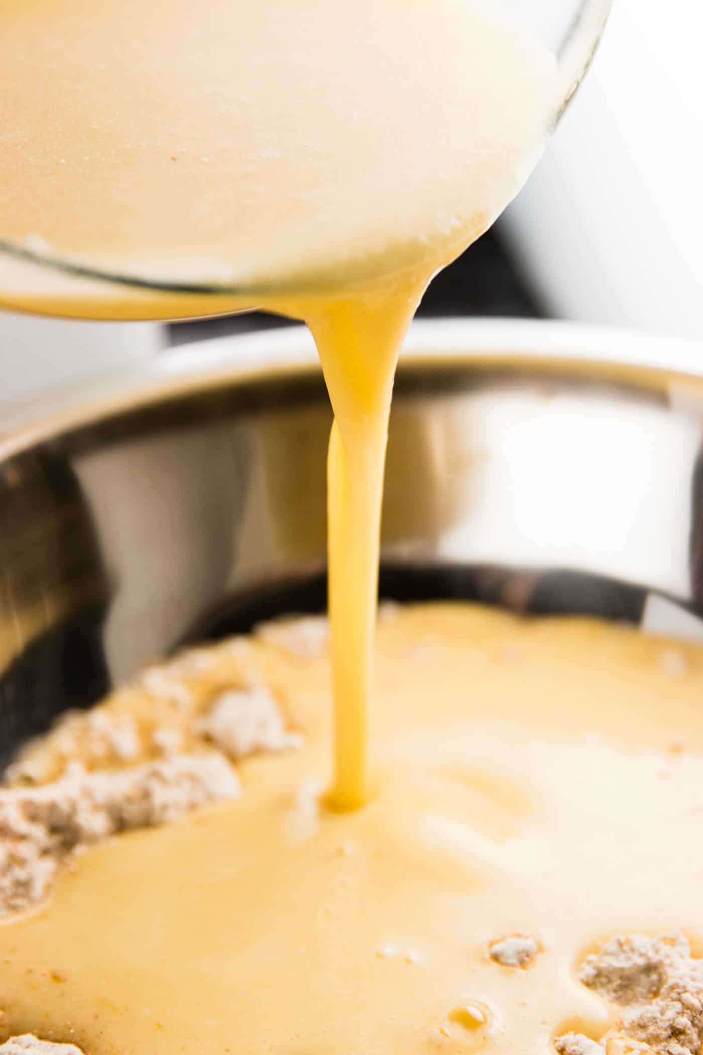 pouring wet ingredients from a bowl into dry ingredients for muffins