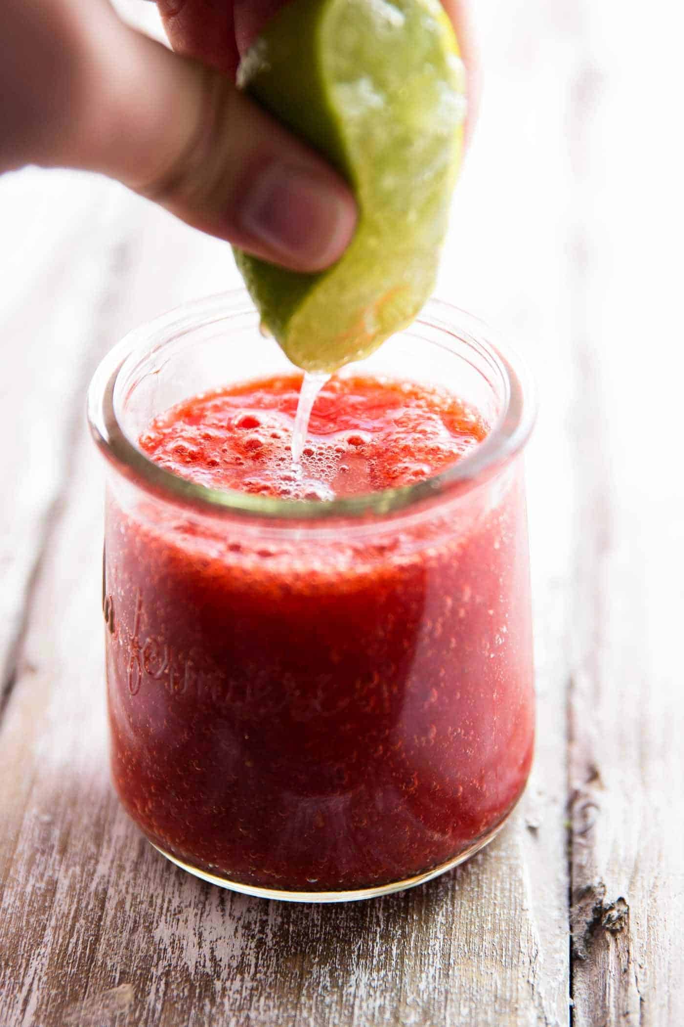 female hand pressing lime into jar with strawberry purée