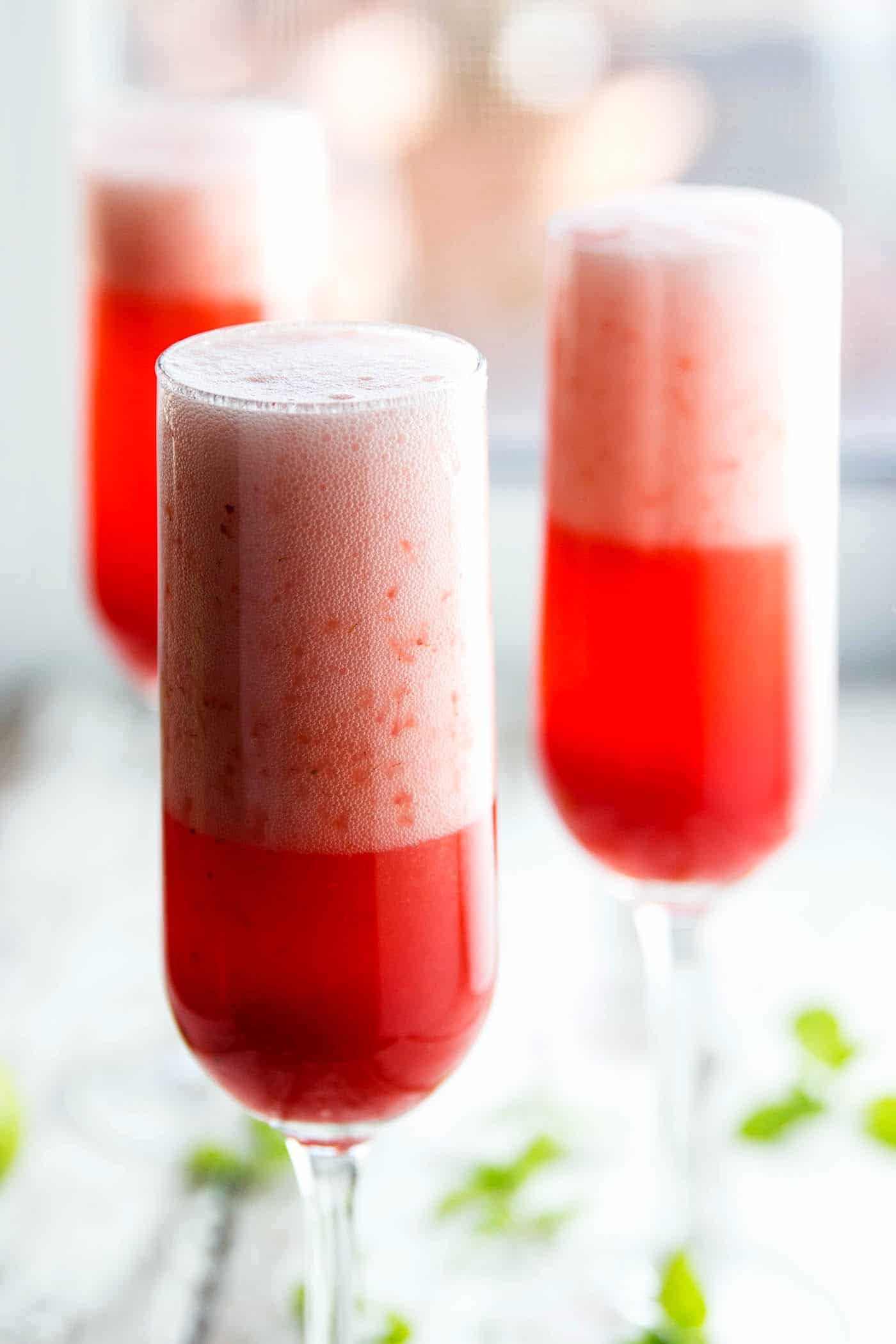 frontal view of three champagne glasses with strawberry champagne cocktail