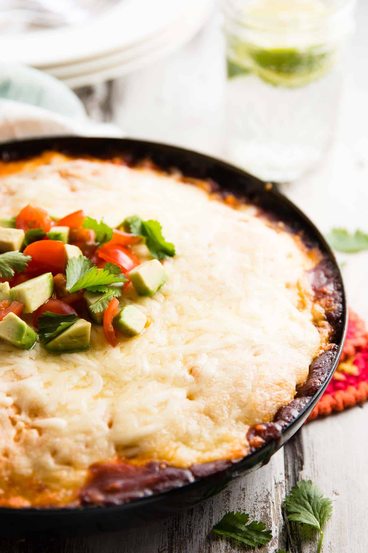 black pan with chicken tamale pie, topped with avocado and tomato