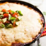 black pan with chicken tamale pie, topped with avocado and tomato