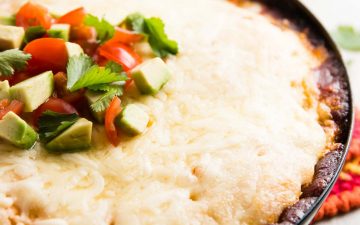 black pan with chicken tamale pie, topped with avocado and tomato