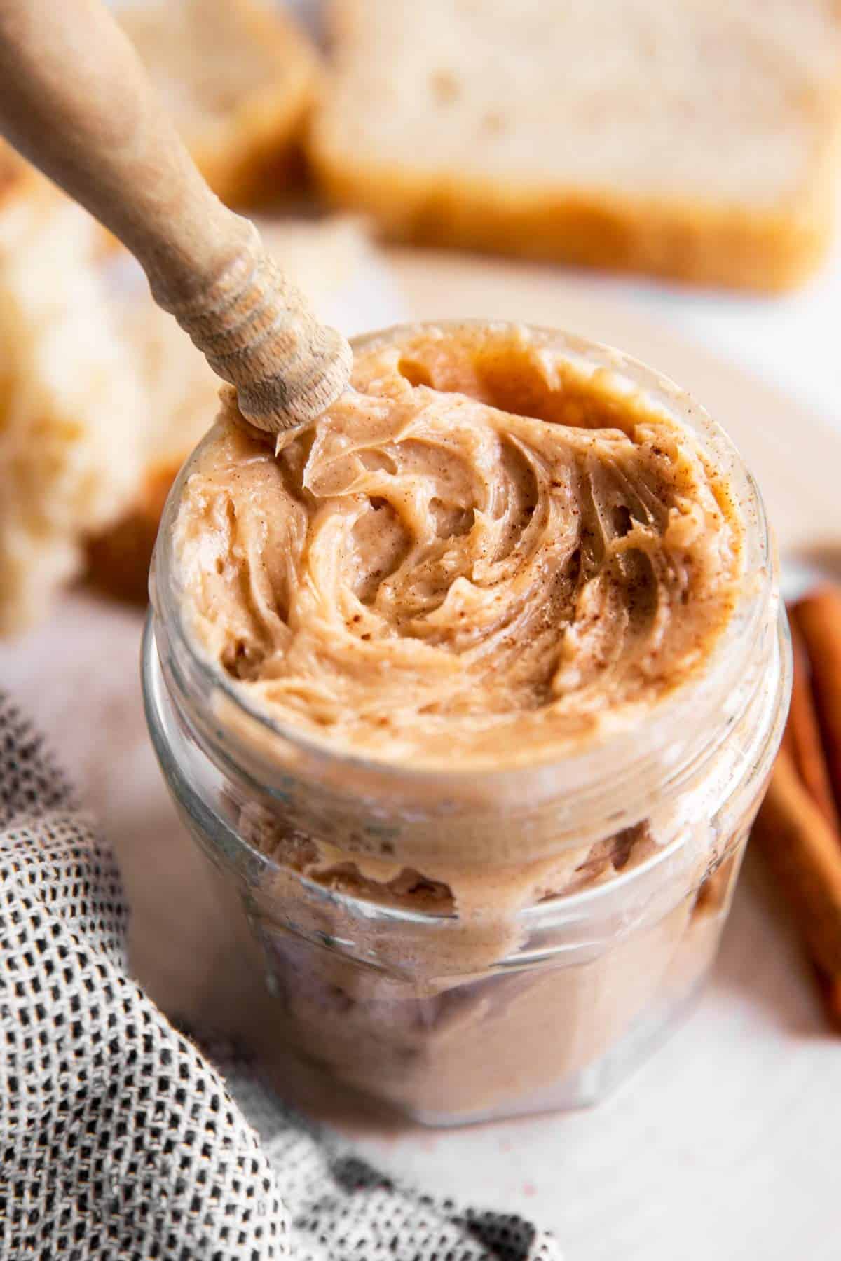 glass jar filled with honey butter in front of bread slices