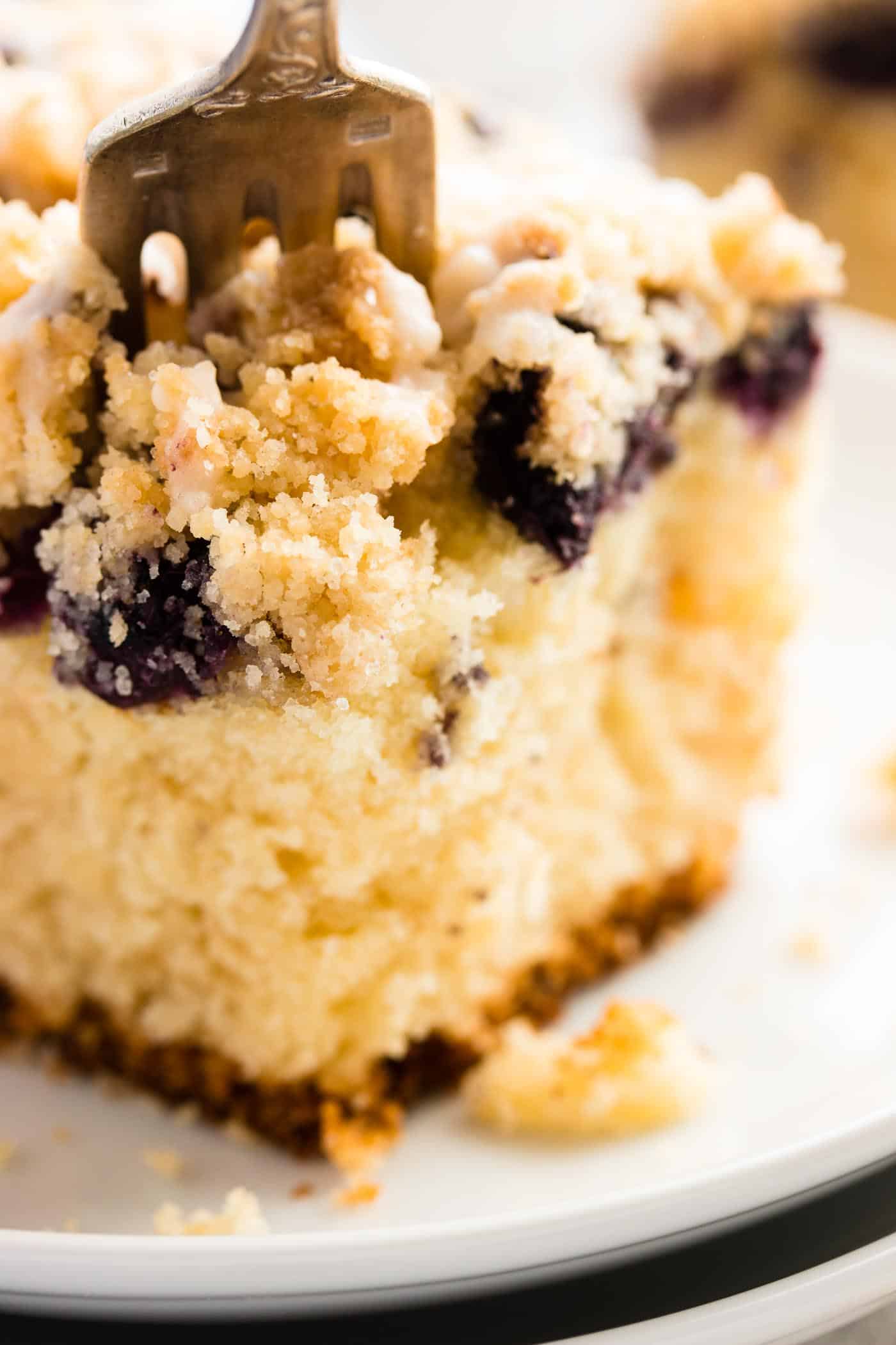 close up photo of fork stuck into a piece of lemon blueberry coffee cake