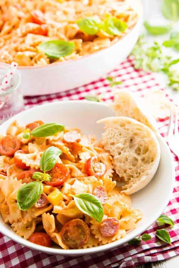 pizza pasta salad in white bowl on red and white chequered tablecloth