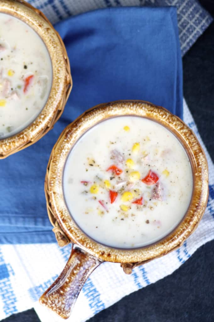 two bowls with ham and corn chowder om blue napkins