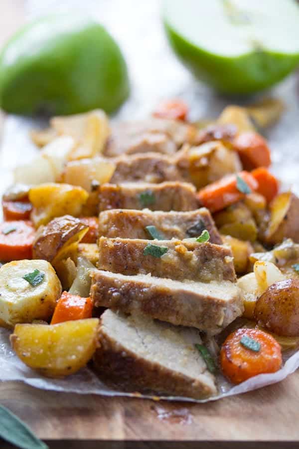 sliced pork tenderloin with vegetables on wooden board