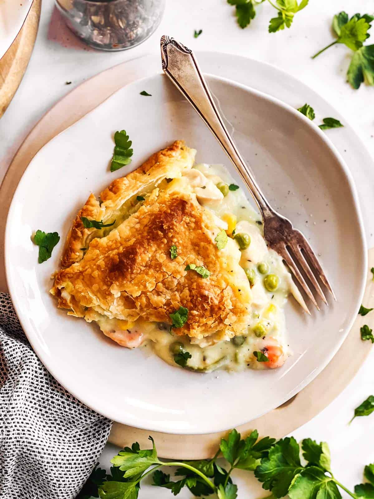 overhead view of a slice of turkey pot pie on a plate, surrounded by parsley