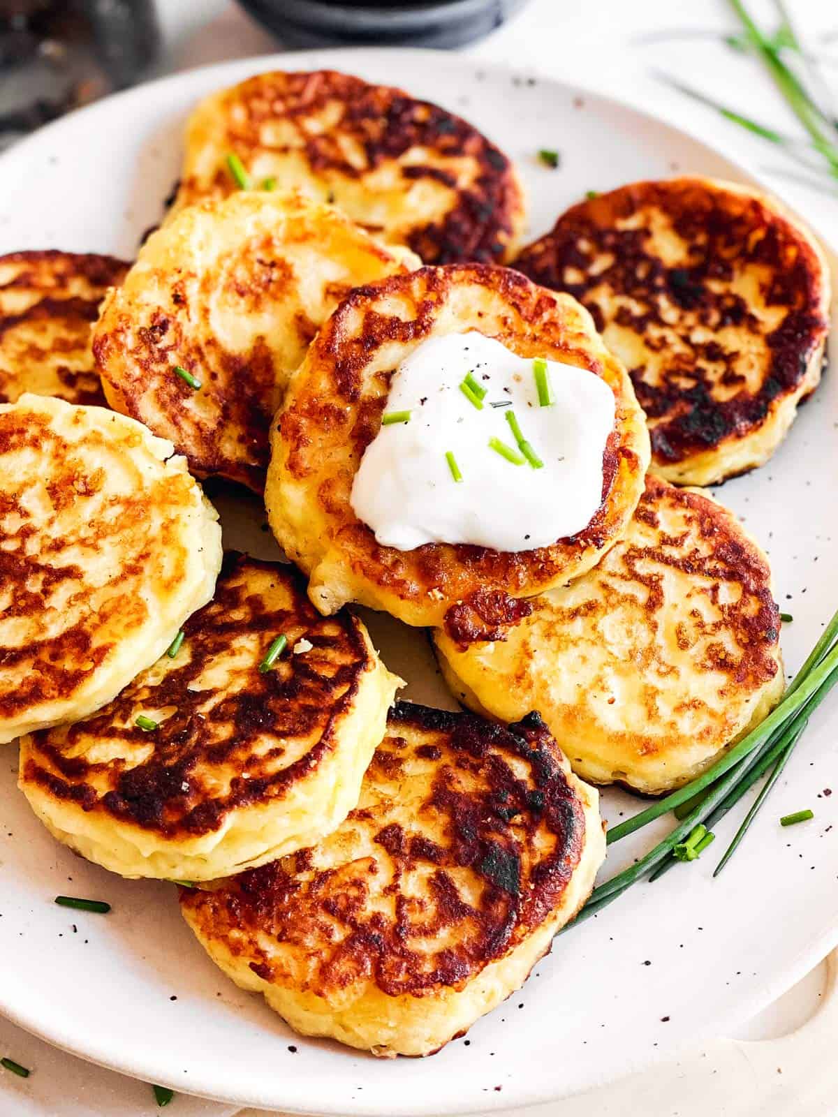 close up view of potato pancakes on white plate with sour cream