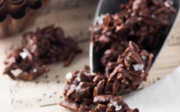 small aluminium scoop with chocolate covered almonds in front of pine cone