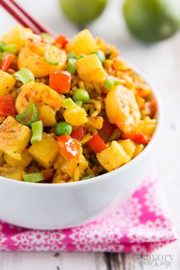 pineapple shrimp fried rice in white bowl on pink napkin