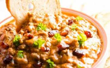 dipping a bread chip into a bowl with crock pot bbq bacon cheeseburger dip