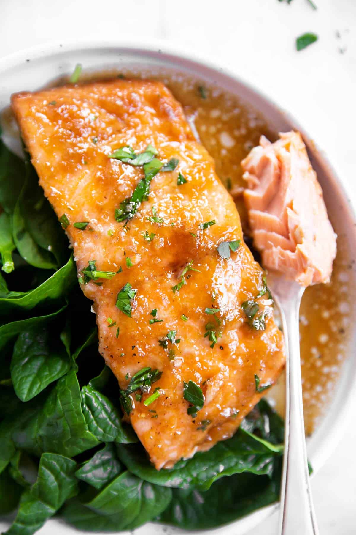 overhead view of honey garlic salmon bake in foil with spinach on plate