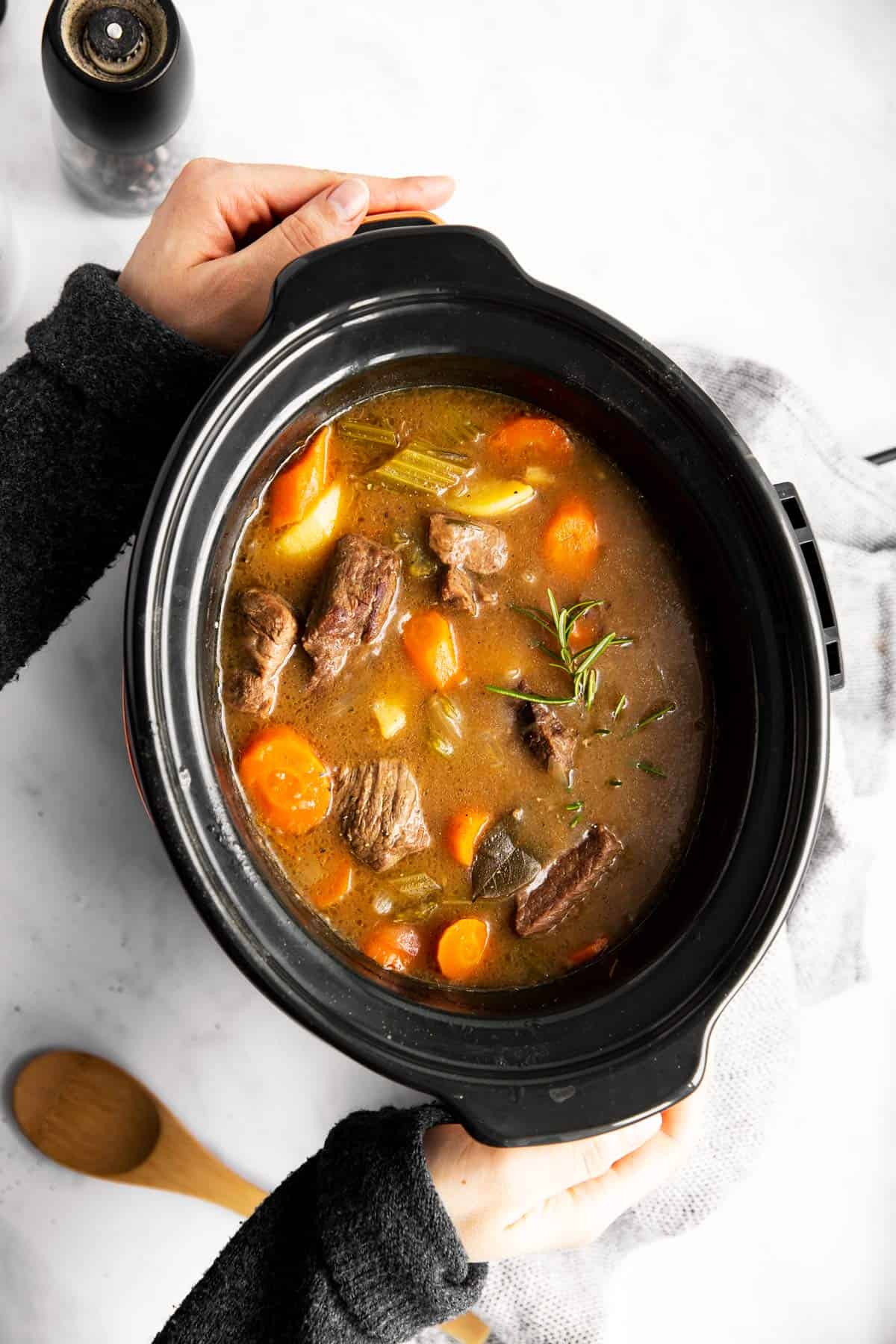 woman holding a slow cooker filled with Irish beef stew