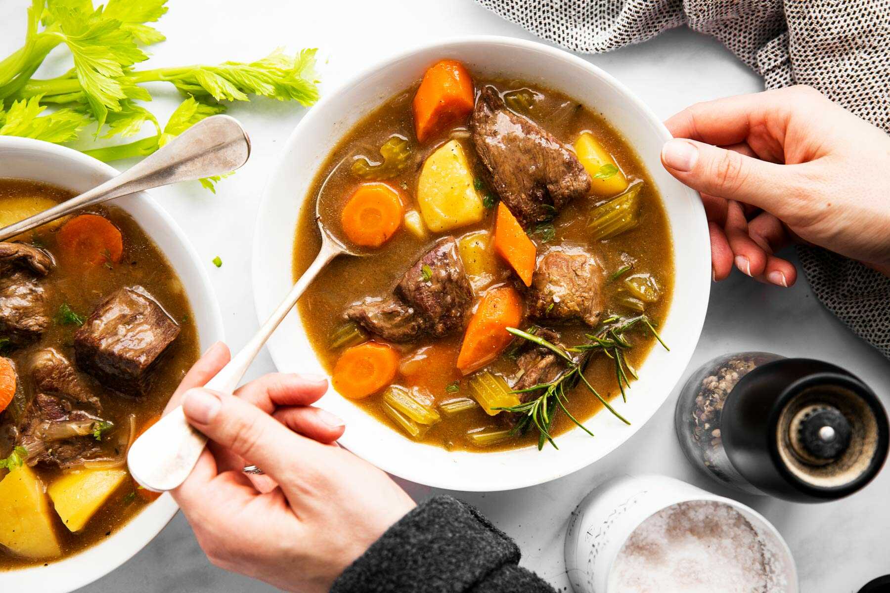 woman dunking a spoon into a bowl of beef stew