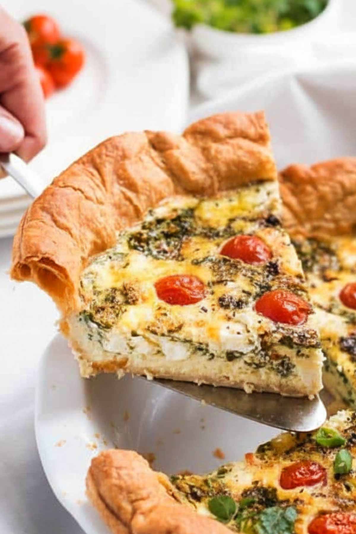 Serving a slice of spinach tomato feta quiche on a cake server.