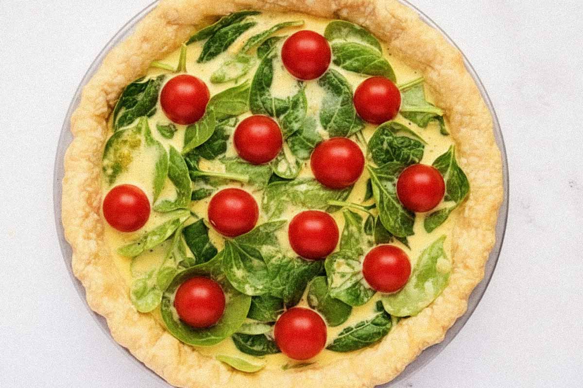 Unbaked tomato spinach feta quiche.