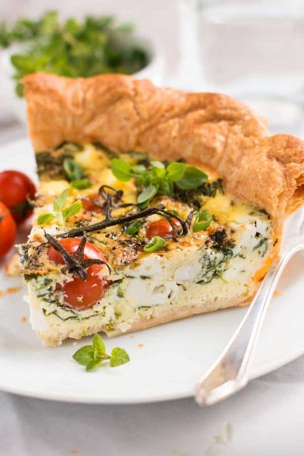 slice of tomato spinach feta quiche on white plate