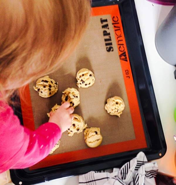 Kid arranging chocolate chip cookie dough.