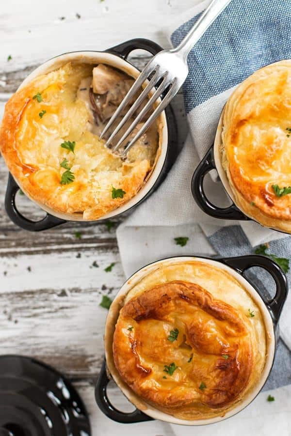 Three individual chicken mushroom pot pies on a dining table.