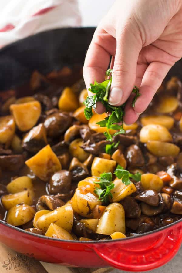 Sprinkling fresh parsley on beef tips and gravy skillet.